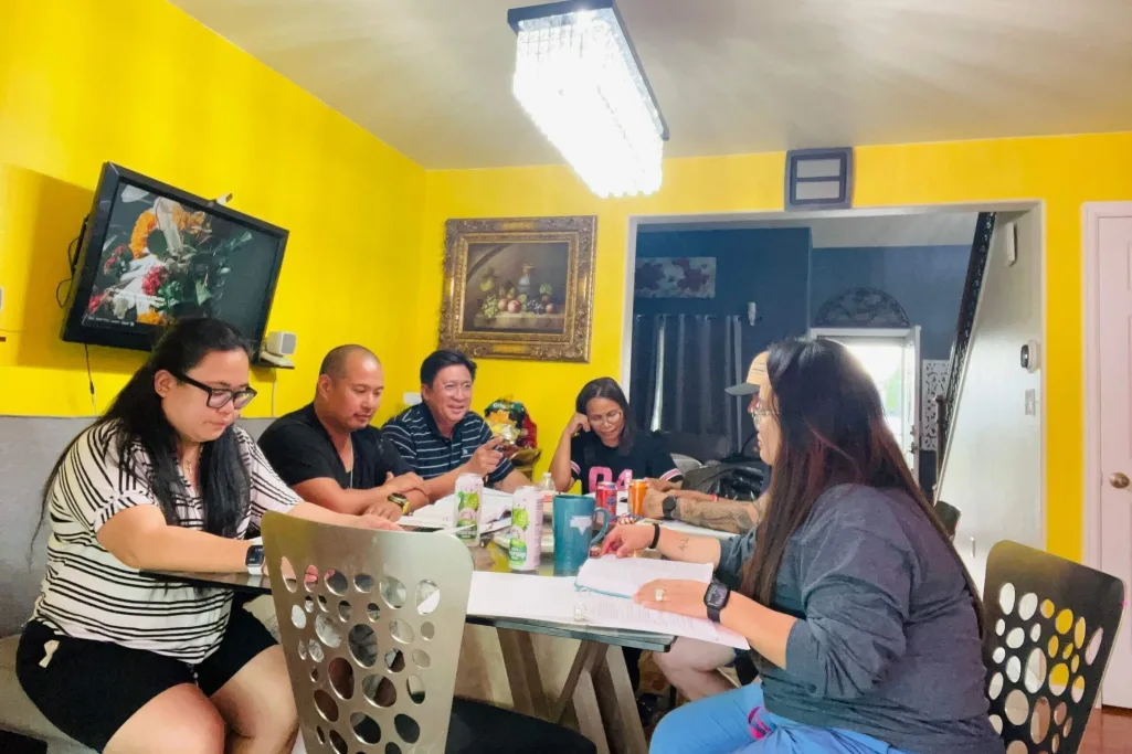 Pastor filipino Arod Javier conversa com pequeno grupo em círculo, com Bíblias abertas, em igreja simples e acolhedora no Col