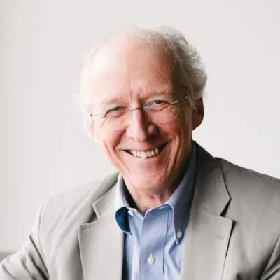 John Piper fala em púlpito durante conferência para líderes evangélicos, com plateia atenta ao fundo.
