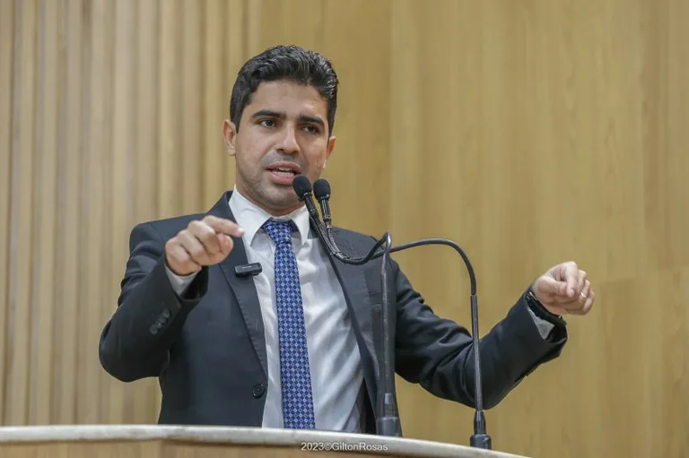 Pastor Diego no púlpito com expressão séria, gesticulando durante pronunciamento sobre intolerância religiosa, com Bíblia abe