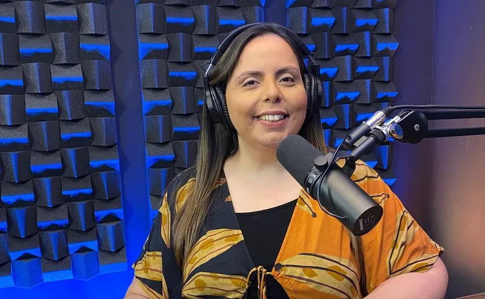 Pastora Helena Raquel ora com mãos postas sobre Bíblia aberta em púlpito iluminado, defendendo igreja que manteve intercessão