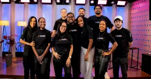 Cantor gospel em palco com violão, banda ao fundo e plateia, em evento em Salvador, Bahia. Projeto gratuito seleciona talento