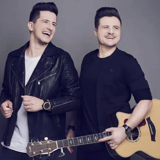 Dupla André & Felipe canta em palco ao ar livre na Praça da Matriz de Araras, com público evangélico e bandeirinhas juninas a