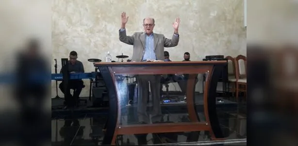 Pastor João Celso (João Messa dos Santos) pregando em um púlpito na Assembleia de Deus de Sooretama, com fiéis ao fundo, dura